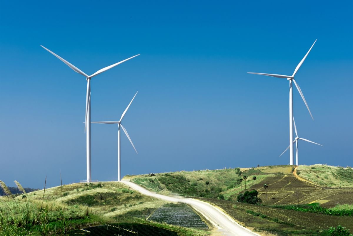 Wind turbines on a green hillside under a blue sky